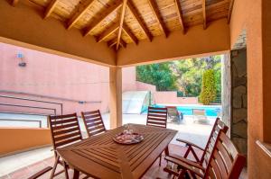 Une table et des chaises en bois sont disponibles sur la terrasse. dans l'établissement Villa Hillcrest Panorama by Ezoria Villas, à Moniatis