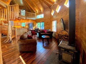 una sala de estar con sofás y una chimenea en una cabaña de madera. en OR Luxury yurt-like home in Bretton Woods with private beach firepit AC fishing and trails, en Carroll