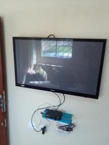 a flat screen tv hanging on a wall with a video game controller at Casas Aconchego do Mar in Japaratinga