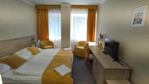 a hotel room with a bed and a desk with a television at Parkhotel Sokolov in Sokolov