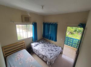 a small bedroom with two beds and two windows at Casas Aconchego do Mar in Japaratinga