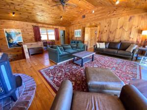 a living room with couches and a tv in a cabin at Amazing lakefront home in the White Mountains with game room theater in Whitefield