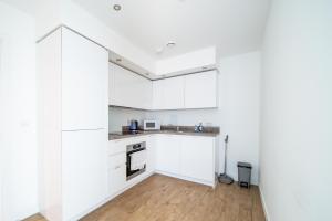 a kitchen with white cabinets and a wooden floor at LiveStay-Modern One Bed Apartment in Private Building in Luton