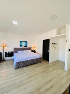 Habitación grande de color blanco con cama grande y suelo de madera. en Habitación Ejecutiva cómoda y acogedora - Centro de Manta, en Manta