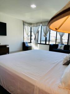 1 cama blanca grande en una habitación con ventanas en Habitación Ejecutiva cómoda y acogedora - Centro de Manta, en Manta