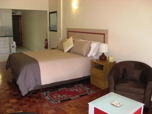 Tweed Valley Lodge في بريدج تاون: غرفة نوم بسرير كبير وكرسي