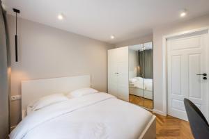 a white bedroom with a bed and a mirror at Powiśle Chic Apartment in Warsaw