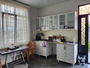 a kitchen with white cabinets and a sink and a table at MITE Hotel in Chakvi