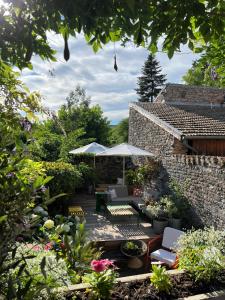 eine Terrasse mit Stühlen und Sonnenschirmen im Garten in der Unterkunft La maison des couturières in Cluny