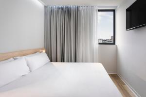 una camera con un letto bianco e una finestra di B&B HOTEL Famalicão a Vila Nova de Famalicão