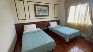 a small room with two beds and a window at Condo D 'Savoy 3 Room in Kampong Alor Gajah