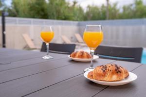 Dois copos de sumo de laranja e croissants numa mesa de madeira. em Kuća za odmor Sara em Privlaka