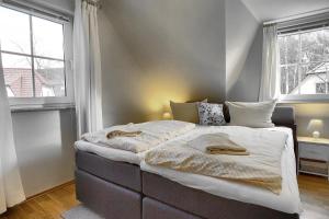 two beds in a bedroom with two windows at Am Deich 43 in Zingst