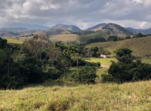 Blick auf ein Feld mit Bäumen und Bergen in der Unterkunft Vivenda dos Guaranys - uma imersão na natureza - Loft in Conservatória