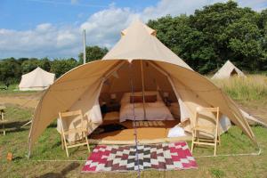 a large tent with chairs and a bed in it at Gresham Hall Glamping in Aylmerton