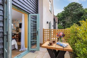 un patio con una mesa de madera y una puerta de cristal en The Duke on The Test, en Romsey