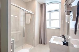 een witte badkamer met een douche en een wastafel bij Hotel MeraPrime Gold Lisboa in Lissabon