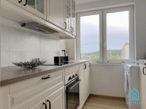 a kitchen with white cabinets and a large window at Jacket Room in Gdańsk