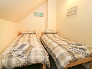 two beds with plaid sheets in a room at The Pebbles in Hornsea