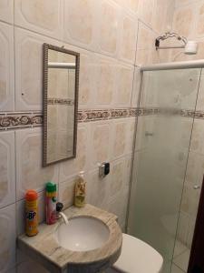 a bathroom with a sink and a shower with a mirror at Hostel Lumiar da Serra in Tiradentes