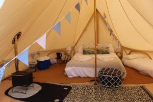 a tent with two beds and a rug in a room at Gresham Hall Glamping in Aylmerton