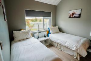 twee bedden in een kamer met een raam bij Holmestead Cottage 