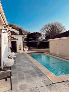 een zwembad in een tuin met een bankje naast een huis bij Ebony Moon in Mthatha