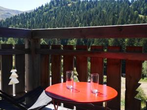 a red table on a deck with glasses on it at Résidence récente au coeur des monts du Cantal in Laveissière