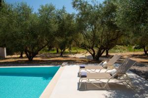 a pair of lounge chairs next to a swimming pool at villa-agrielia in Nikiana