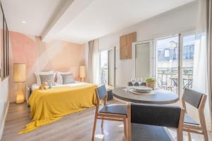 um quarto com uma cama amarela e uma mesa com cadeiras em Yuna Les Halles - Serviced Apartments em Paris