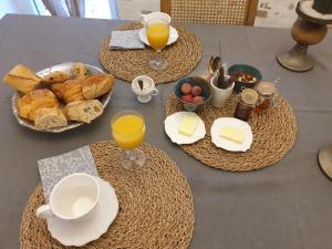 a table with a breakfast of bread and orange juice at Chambre de charme dans une propriété du 18ème in Roquettes