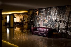 a leather couch in a lobby with a large mural at Park Hotel Sankt Peterburg in Plovdiv