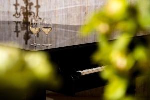 Dois copos de vinho branco sentados num piano. em Park Hotel Sankt Peterburg em Plovdiv