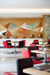 comedor con mesas, sillas y paredes de madera en Ibis Balikpapan, en Balikpapan