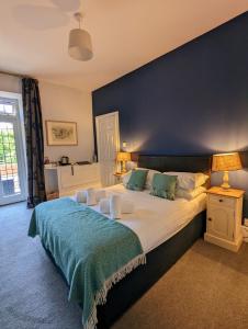 a bedroom with a large bed with a blue wall at The Hunters Inn in Martinhoe