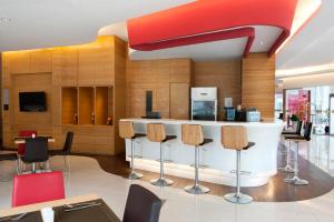 a lobby with a bar with chairs and a tv at Ibis Balikpapan in Balikpapan