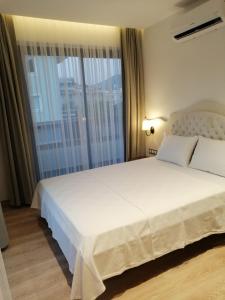 1 dormitorio con 1 cama blanca grande y ventana grande en Channel Suites en Fethiye