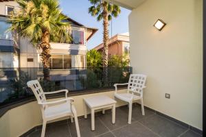 a balcony with three chairs and a table and a window at Channel Suites in Fethiye