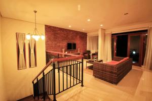 sala de estar con escalera y pared de ladrillo en Villa Dago Syariah, Familiy Only, View Indah ke Bukit Dago, en Bandung
