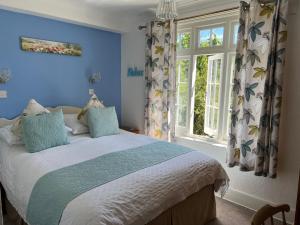 Un dormitorio con una cama con paredes azules y una ventana en Bedford Lodge en Shanklin