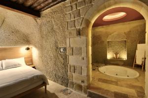 a bedroom with a bed and a bath tub at Evanthia Cave Suites in Ürgüp