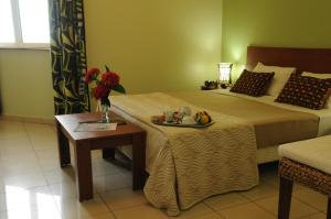 a bedroom with a bed and a table with a tray of food at Hotel Maharajah in Mamoudzou