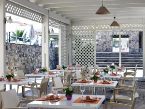une salle à manger avec des tables et des chaises blanches dans l'établissement Atlantica Thalassa Hotel, à Kos