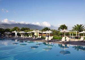 ein großer Pool mit weißen Stühlen und Sonnenschirmen in der Unterkunft Atlantica Thalassa Hotel in Kos-Stadt