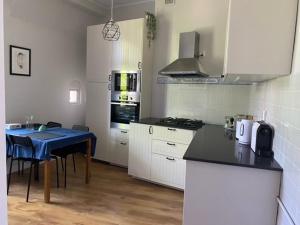 uma cozinha com armários brancos e uma mesa azul em Apartament Władysława IV em Sopot