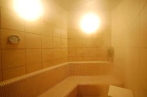a bathroom with a tub with two lights on the wall at Anshin Oyado Ginza Shimbashi Station - For Men in Tokyo +47 photos