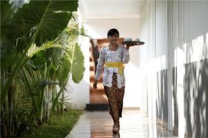 Una mujer caminando por un pasillo con un sombrero en la cabeza en 7 Bidadari Hotel Seminyak, en Seminyak