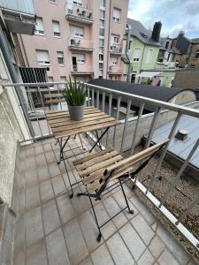 a balcony with a wooden bench and a table with a plant at rooms train station in Luxembourg