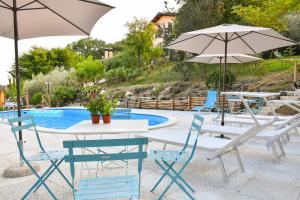 a table and chairs with umbrellas next to a pool at Agriturismo L'Arte del Verde in Amelia