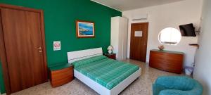 ein grünes Schlafzimmer mit einem Bett und einem Stuhl in der Unterkunft Lincoln B&B in Caserta